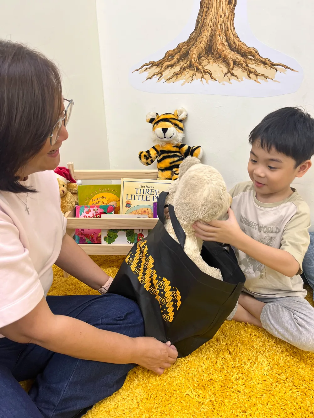 A teacher opening a story bag as a smiling child lifts out a soft toy